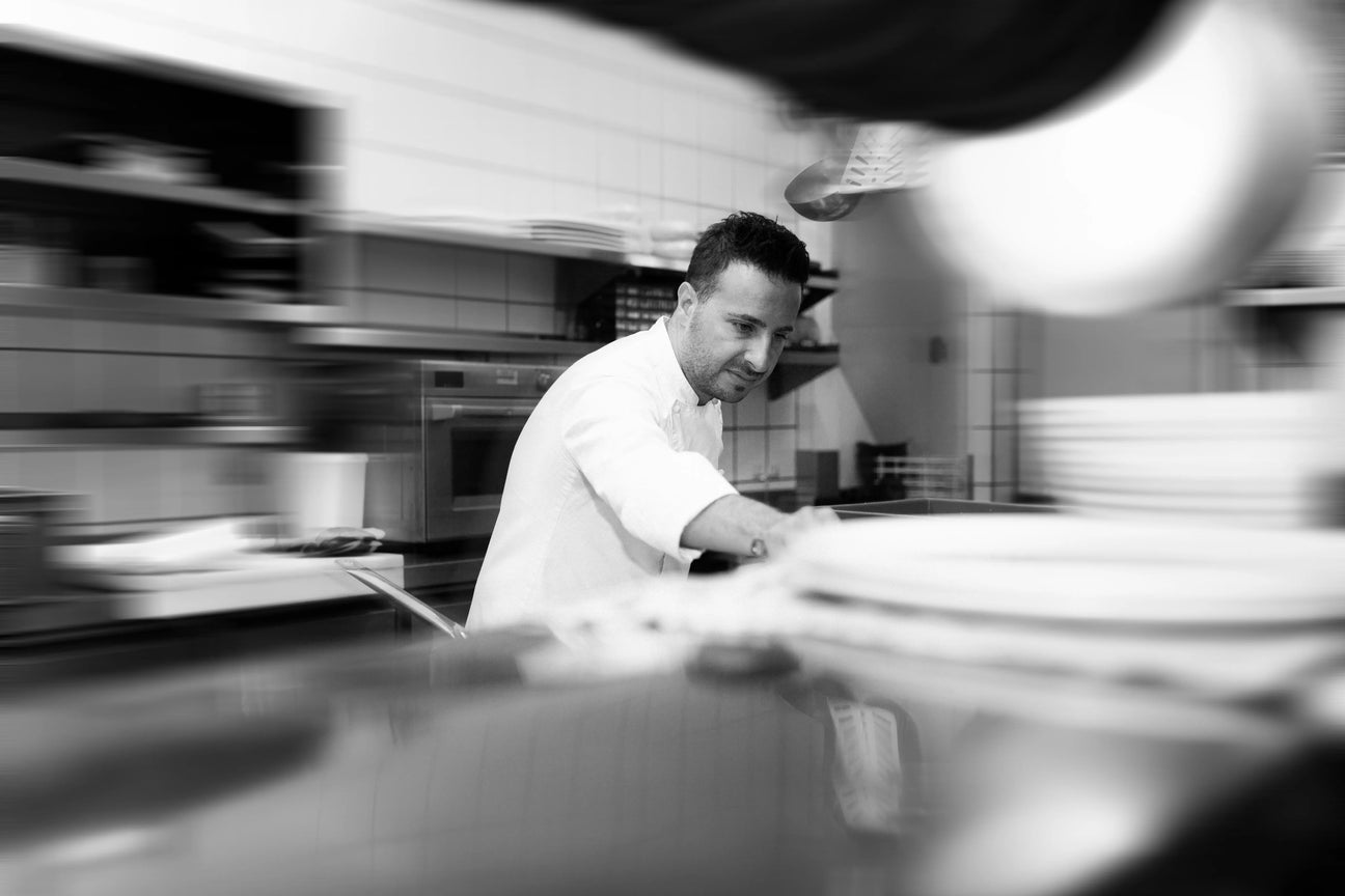 Schwarz-Weiß-Aufnahme von Koch Salvatore bei der fokussierten Arbeit in einer Restaurantküche.
